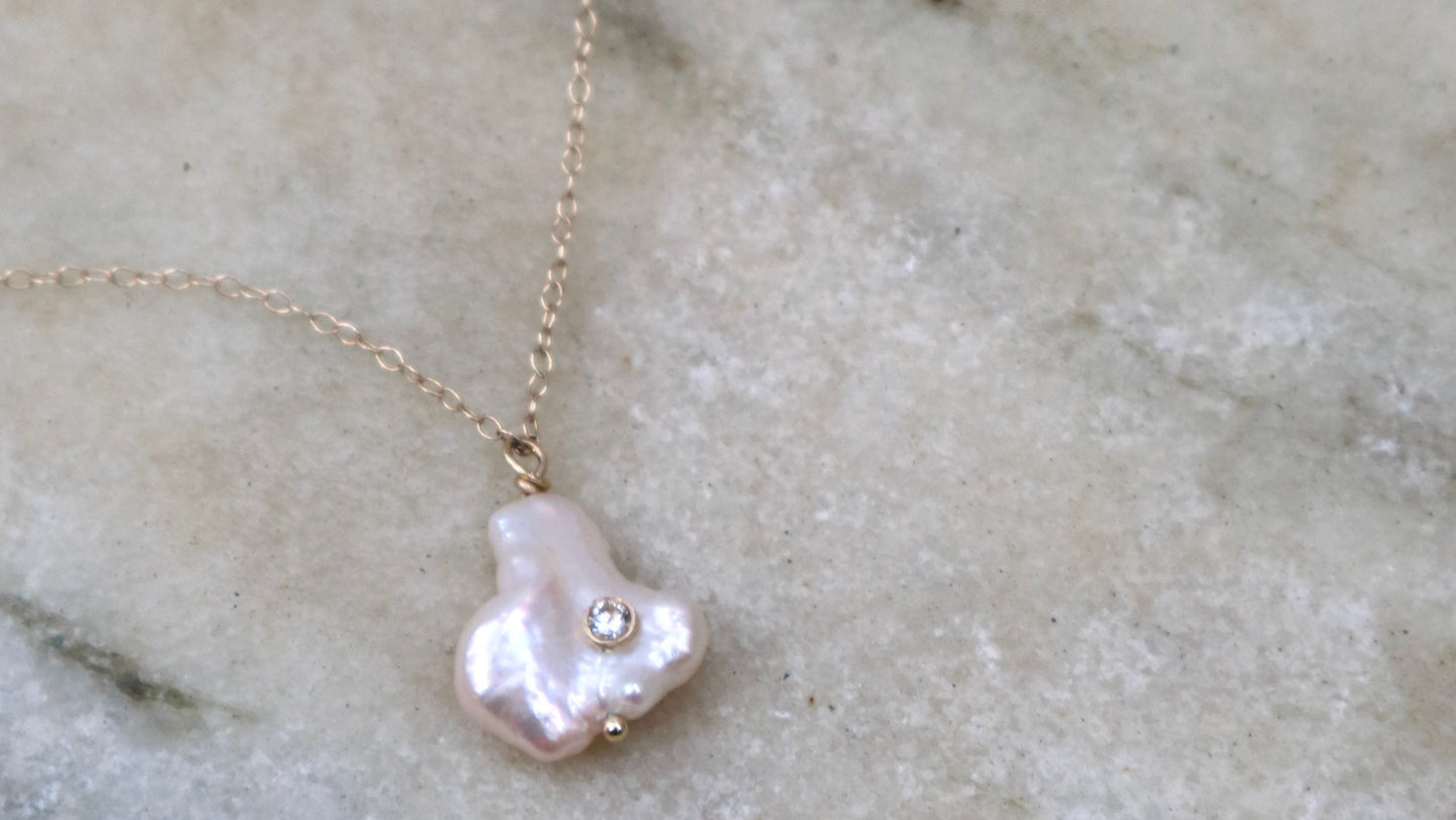 Pearl necklace with a gold chain on a marble background