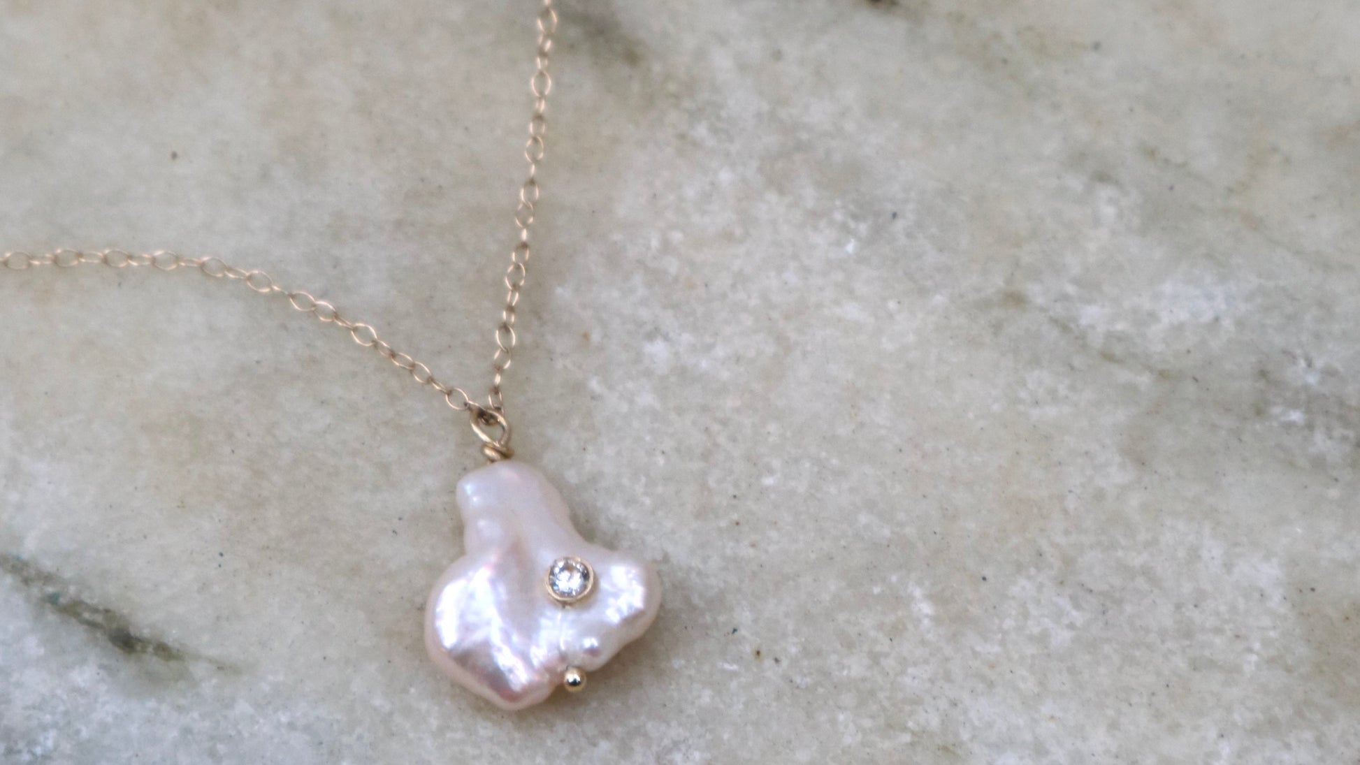 Pearl necklace with a gold chain on a marble background