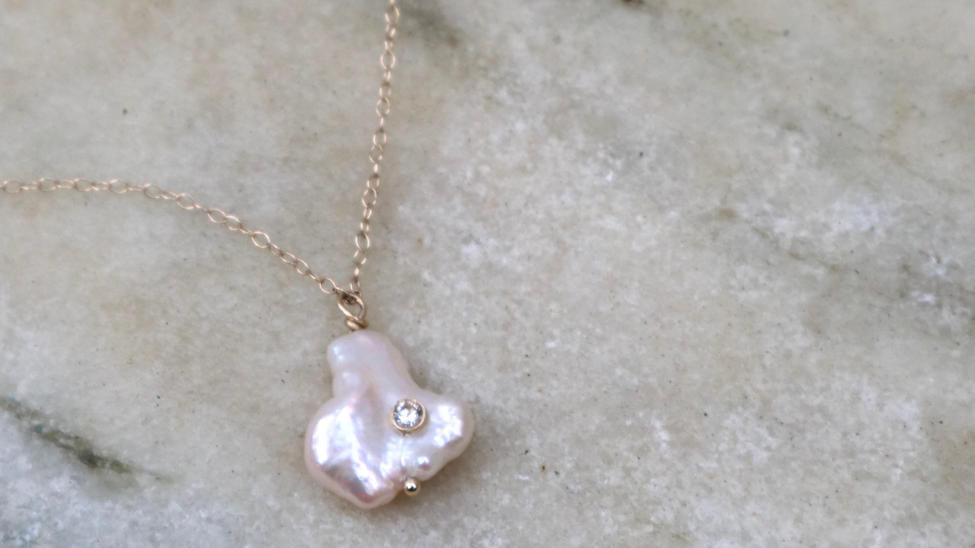 Pearl necklace with a gold chain on a marble background